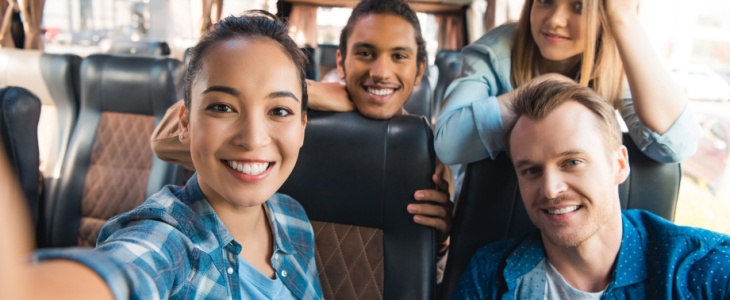 Four happy people rising a charter bus